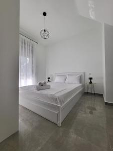 ein weißes Schlafzimmer mit einem großen Bett und einem Fenster in der Unterkunft Thἕros Exceptional Residence in Néa Péramos