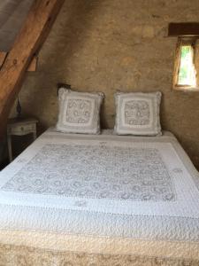 a white bed with two pillows in a room at La Parenthèse - Studio atypique - Piscine - Proche Le Mans in Amné-en-Champagne