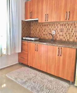 a kitchen with wooden cabinets and a sink and a rug at Plaja Yakın Dağ ve Deniz Manzaralı 1+1 Daire in Gokceada Town