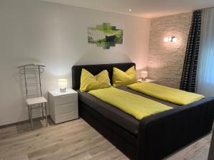 a bedroom with a black bed with yellow sheets and a yellow blanket at Appartement Butterfly in Saas-Grund