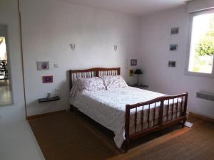 Schlafzimmer mit einem Holzbett mit weißer Bettwäsche und einem Fenster in der Unterkunft Maison de vacances au calme entre St Malo et Cancale in Saint-Méloir-des-Ondes