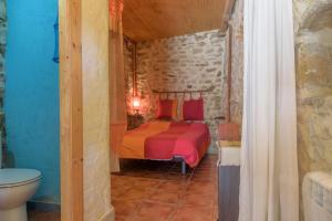 1 dormitorio con cama y pared de piedra en El Telar, en Rasines