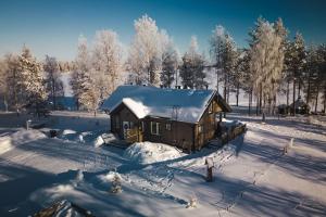 una cabaña en un campo cubierto de nieve con árboles en Your Peace Of Lapland, en Rovaniemi