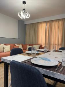 a dining room with a table with chairs and a couch at Shehapi apartment in Kavajë