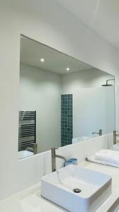 uma casa de banho com um lavatório branco e um espelho grande em Dona Maria 66 na Praia da Luz