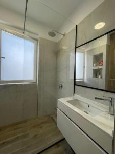 a bathroom with a sink and a mirror and a window at Shehapi apartment in Kavajë