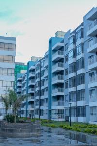 Syokimau的住宿－Indesign Makumbi park studio Apartment D4-5,Syokimau，一座蓝色的公寓楼,前面有棕榈树