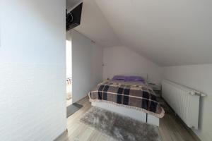 1 dormitorio con 1 cama en una habitación blanca en Csíkcsicsó, 699 Sillok utca, en Ciceu