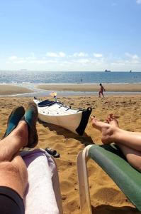 Sea Proche في سانداون: شخصان يستلقون على الشاطئ بجوار قارب