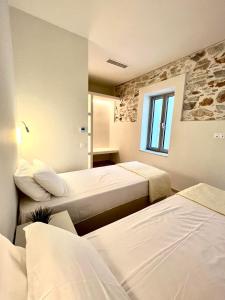 a hotel room with three beds and a window at Kefi House Skiathos in Skiathos
