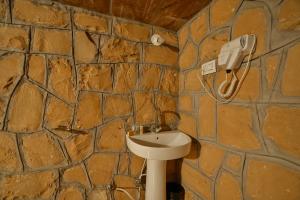 Baño con paredes de piedra, lavabo y teléfono en The Carvaans Resort, en Jaisalmer