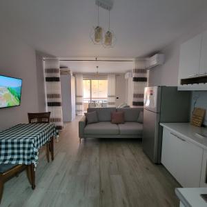 een woonkamer met een bank en een tafel en een keuken bij Small Studio near the Olimpik Park in Tirana