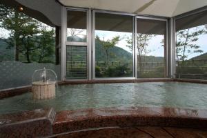 a swimming pool with a fountain in a room with windows at Gyokutei in Hakone