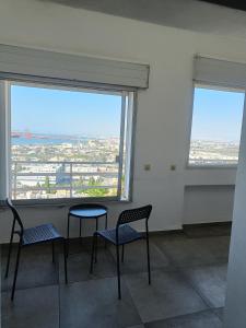 Duas cadeiras e uma mesa num quarto com janelas em Bella Vista in Haifa em Haifa