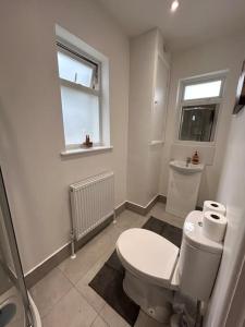 a bathroom with a white toilet and a window at Bali Bliss Garden Flat with Parking in Enfield