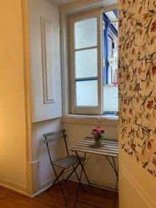 a table and a chair in a room with a window at Saudade Guest House in Lisbon