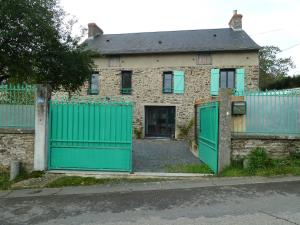uma velha casa de tijolos com portas verdes e uma cerca em L' ALBIZIA em Saint-Martin-de-Sallen