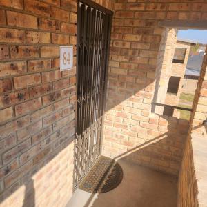 a brick wall with a gate on the side of a building at Two Bedroom townhouse THE PINES ALBERTSDAL in Alberton