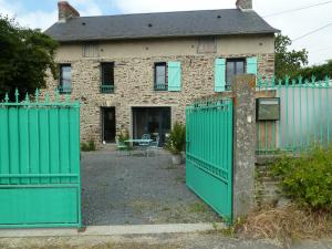 uma casa velha com portões verdes em frente em L' ALBIZIA em Saint-Martin-de-Sallen
