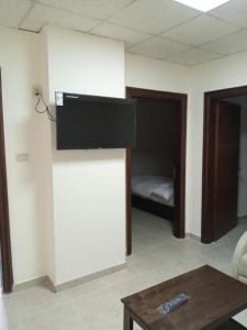 uma sala de estar com uma TV de tela plana na parede em Al Ghadeer Hotel الغدير للشقق الفندقيه em Amã