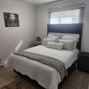 1 dormitorio con 1 cama grande con sábanas y almohadas blancas en Two Bedroom townhouse THE PINES ALBERTSDAL en Alberton