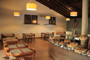a restaurant with tables and chairs and a counter with food at Sarana Praia Hotel in Porto Seguro