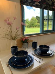 una mesa con dos cuencos azules y platos en ella en St. Kew Shepherd Huts en Wadebridge