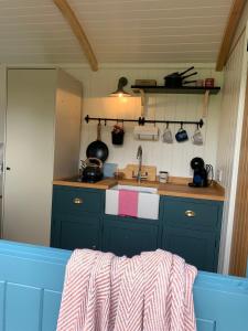una cocina con armarios azules y fregadero en St. Kew Shepherd Huts en Wadebridge
