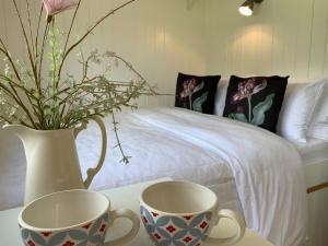 due tazze su un tavolo accanto a un letto di St. Kew Shepherd Huts a Wadebridge