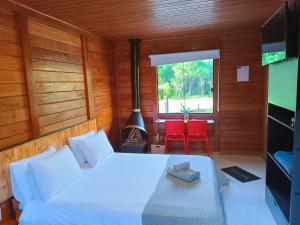 um quarto com uma cama, uma lareira e uma televisão em Refúgio Allamanda Flats em Visconde de Mauá