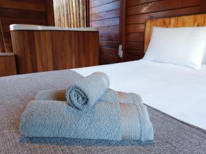 uma pilha de toalhas sentadas numa cama em Refúgio Allamanda Flats em Visconde de Mauá