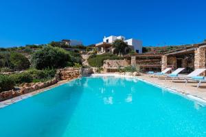 a large blue swimming pool with chairs and a house at BLUE VILLA in Kampos Paros