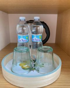 zwei Flaschen Wasser und zwei Gläser auf einem Tablett in der Unterkunft CASA SACURI in Rudalza