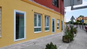 a yellow building with white windows on a street at Apartamentos y estudios EL CENTRO in Vargas