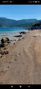 a beach with rocks and water and mountains in the background at Casa de Laza Apartments in Herceg-Novi