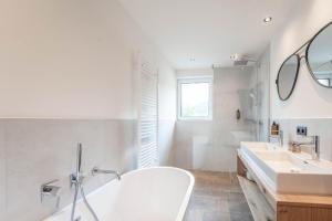 a white bathroom with two sinks and a tub at Löckerwirt in Sankt Margarethen im Lungau