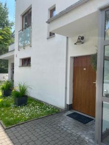 a white house with a brown door and plants at Apartament Wiktoria Wilanów in Warsaw
