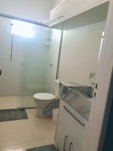 a bathroom with a toilet and a glass shower at Casa aconchegante 303 sul in Palmas