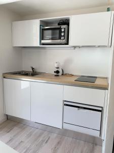 una cucina con armadietti bianchi e forno a microonde di Casetta Lorica Porto Santo Stefano a Porto Santo Stefano