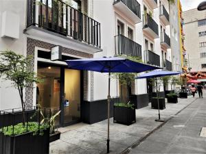 a sidewalk with two blue umbrellas in front of a building at Downtown Ciudad de México in Mexico City