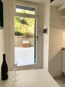 ein Weinglas auf einer Theke neben einem Fenster in der Unterkunft Casetta Lorica Porto Santo Stefano in Porto Santo Stefano
