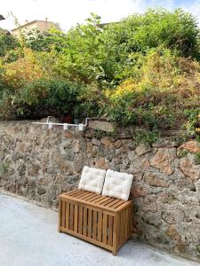 una panchina con due cuscini seduta accanto a un muro di pietra di Casetta Lorica Porto Santo Stefano a Porto Santo Stefano