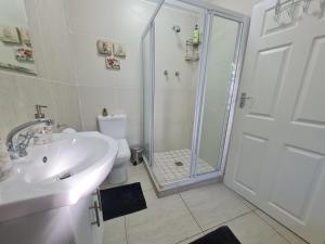 a bathroom with a shower and a sink and a toilet at Sandpiper Self Catering in East London
