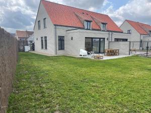a white house with a red roof and a yard at Noordzeehuys in Middelkerke