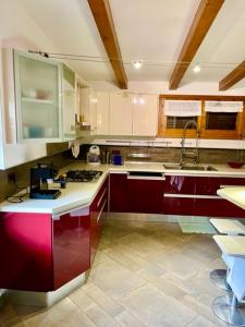 a large kitchen with red cabinets and a sink at Casa Laura in Campolongo +7 photos