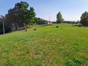 a field with hay bales in front of a house at Domaine Royal Quercy in Monclar-de-Quercy