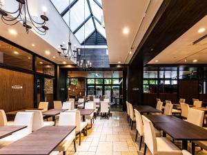 a restaurant with wooden tables and white chairs at APA Hotel Kyoto Eki Horikawadori in Kyoto