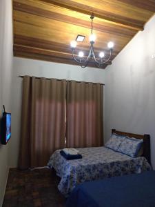 a bedroom with a bed and a chandelier at Hospedagem Caminho do Lago in Cunha