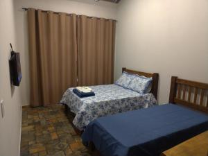 a small room with two beds and a television at Hospedagem Caminho do Lago in Cunha