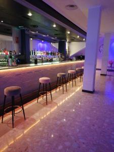 een bar met krukken in een gebouw met paarse verlichting bij Pensión A&E in Manises